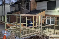 Deck joists and upright framing under construction outside a townhouse