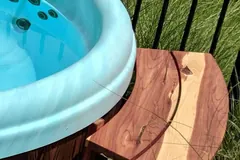 Curved wooden shelf fitted around the outside edge of a round hot tub